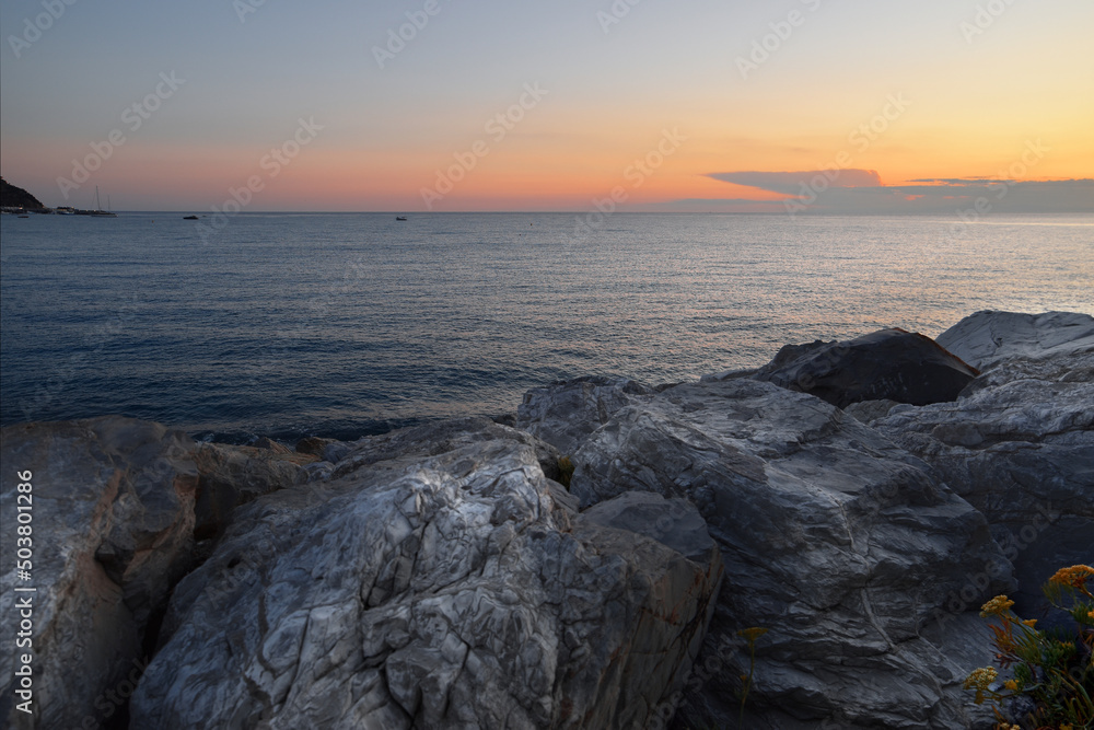 Obraz premium incredible colors and lights, a romantic sunset on the beach facing the sea in the magnificent Liguria