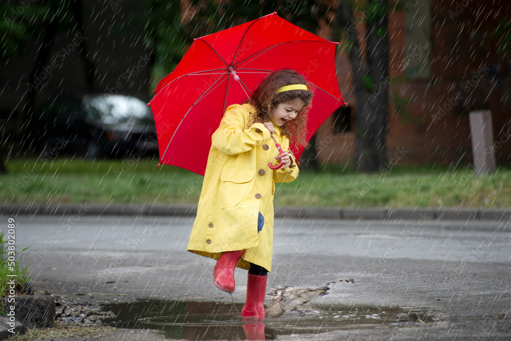 Obraz premium Little girl jumps on the pond in the rain