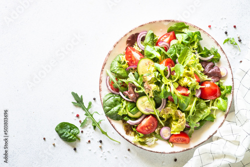 Salad in white plate. Green leaves and vegetables Healthy vegan food, diet food. Top view, copy space.