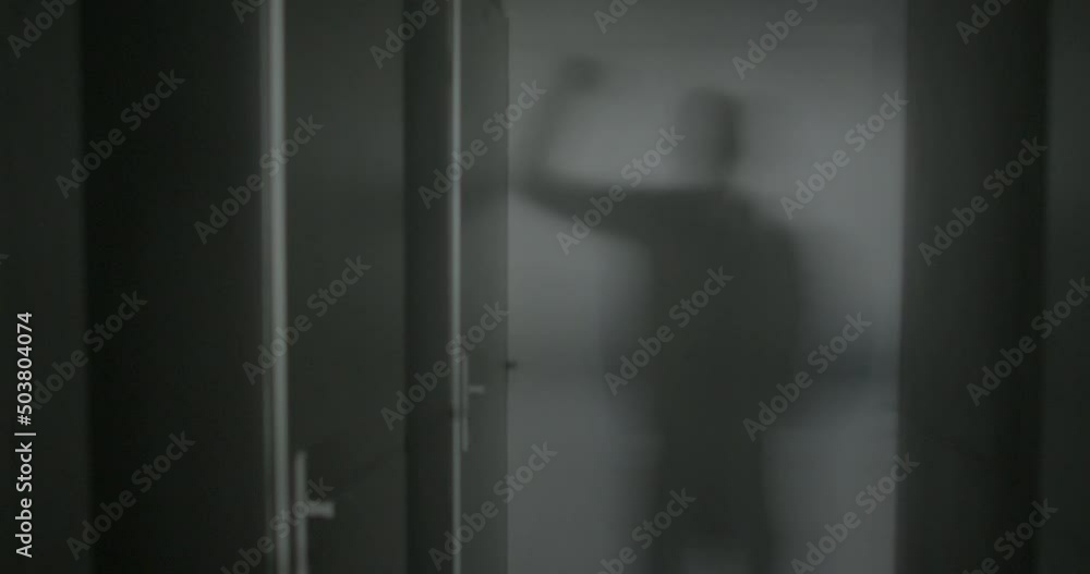 Silhouette of the shadow of a man on the wall, he knocks on the door with his hand. Dark room in the corridor of an apartment building. Signal an arrival. Silhouette of the shadow of a man on the wall, he knocks on the door with his hand. Dark room in the corridor of an apartment building. Signal an arrival.