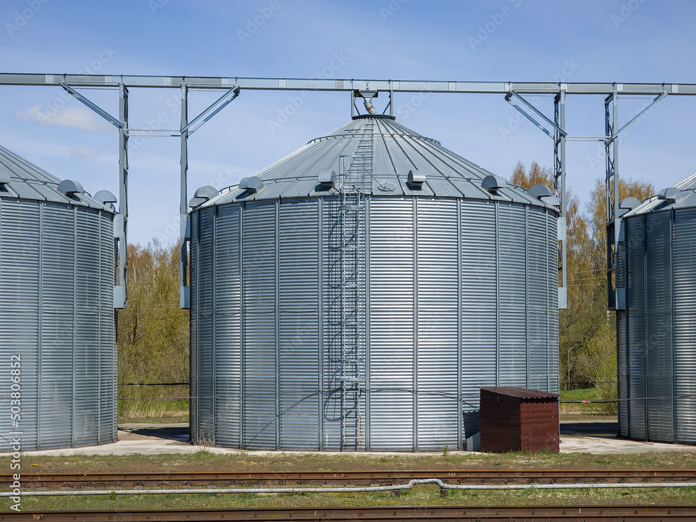 Modern Granary elevator. Silver silos on agro-processing and manufacturing plant for processing drying cleaning and storage of agricultural products, flour, cereals and grain.