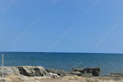 rocky seashore, blue water and blue sky.