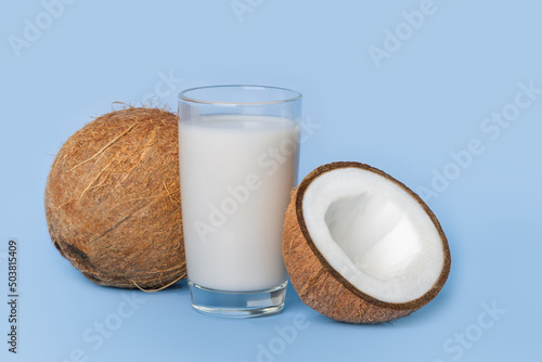 Glass of coconut milk with coconut on blue background