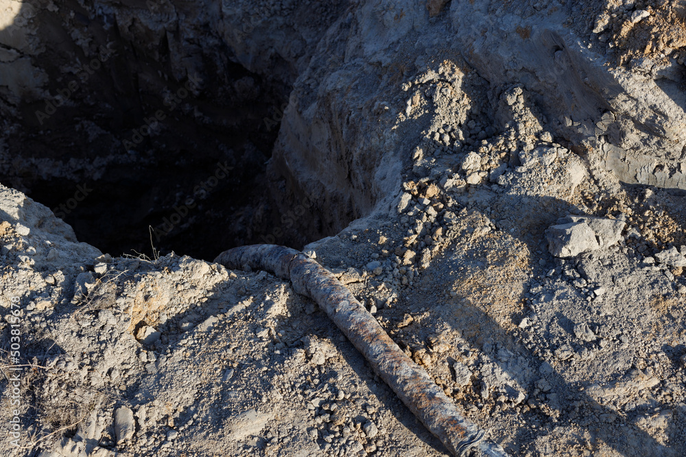 Rusty, thick and old earth cable. Old installation, trench in the ground, hole in the ground Rusty, thick and old earth cable. Old installation, trench in the ground, hole in the ground