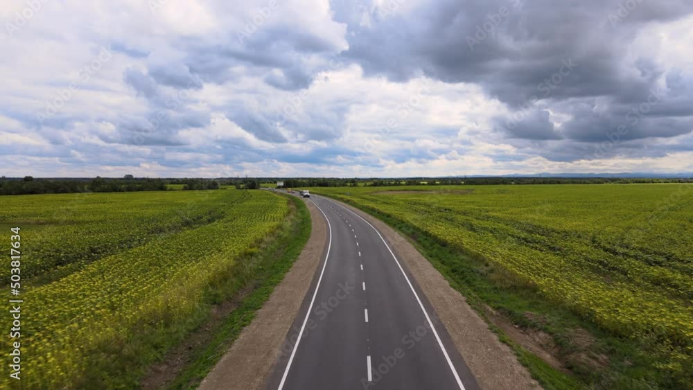 Aerial view of intercity road between green agricultural fields with fast driving cars. Top view from drone of highway traffic Aerial view of intercity road between green agricultural fields with fast driving cars. Top view from drone of highway traffic