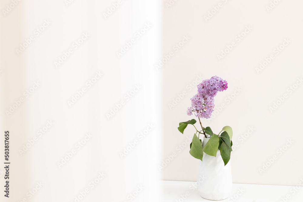 Lilac flowers in white vase on white table