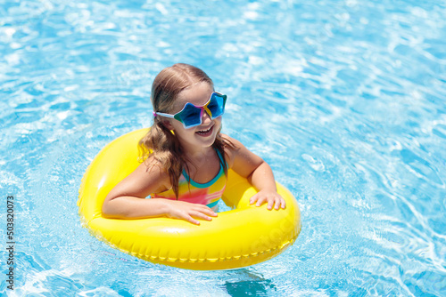 Child on float in swimming pool. Kids sunglasses.