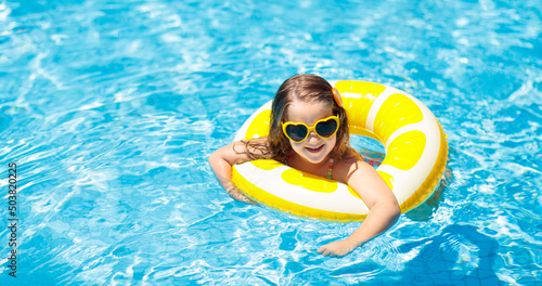 Child in swimming pool on ring toy. Kids swim.