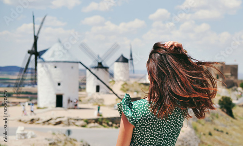 Rear view of a young woman posing against famous old windmills in Consuegra town, Spain