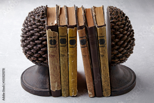 Old shabby books stand between holders in the form of cones photo