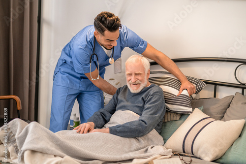 Healthcare worker helping a bedridden person sit up in bed