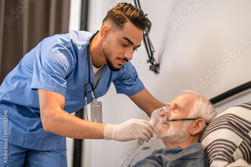 Obraz na plátne Concentrated nurse getting an old man ready for oxygenation