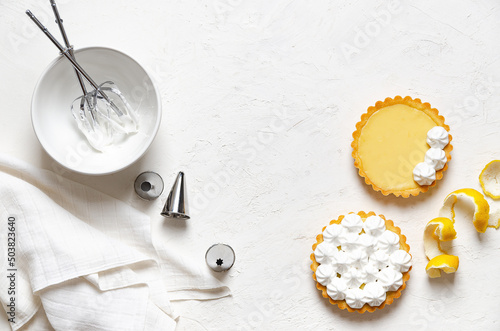 Wallpaper Mural Mini lemon pies with meringue, lemon peel, whisks in meringue, piping nozzles and a white napkin, on a white background with copy space.  Torontodigital.ca