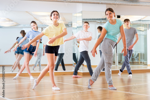 Positive teenage dancers doing dance workout during group class