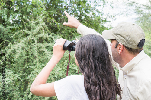 Mature Park Ranger indicates to a young student with binoculars the location of a protected species in a national park photo
