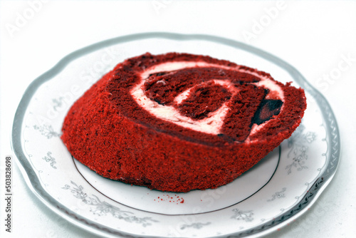 Strawberry Swiss Roll gateau made of rich fluffy spongy cake roll with layers of heavy whipping cream, dried strawberries and creamy cheese, selective focus of a piece of a piece of red rolled cake photo