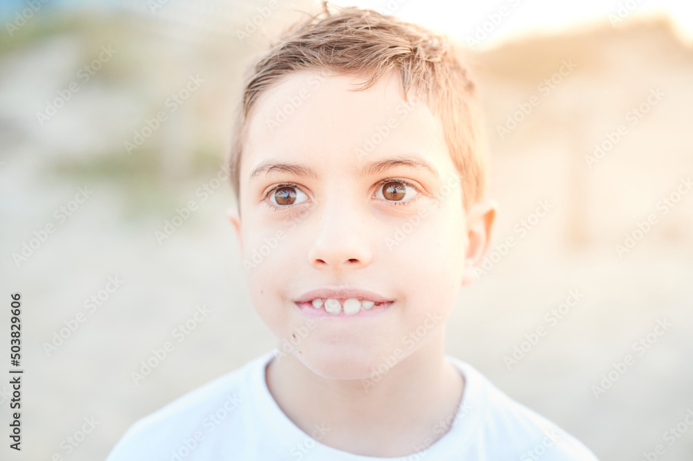 Cute toddler boy portrait outdoors while biting his lower lip. Ten years old happy kid gesturing with his face. Children teeth concept. Cute toddler boy portrait outdoors while biting his lower lip. Ten years old happy kid gesturing with his face. Children teeth concept.