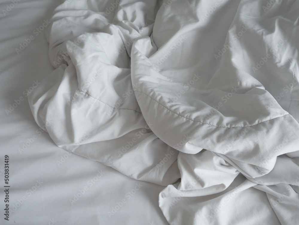 messy white blanket on bedroom after waking up in the morning.