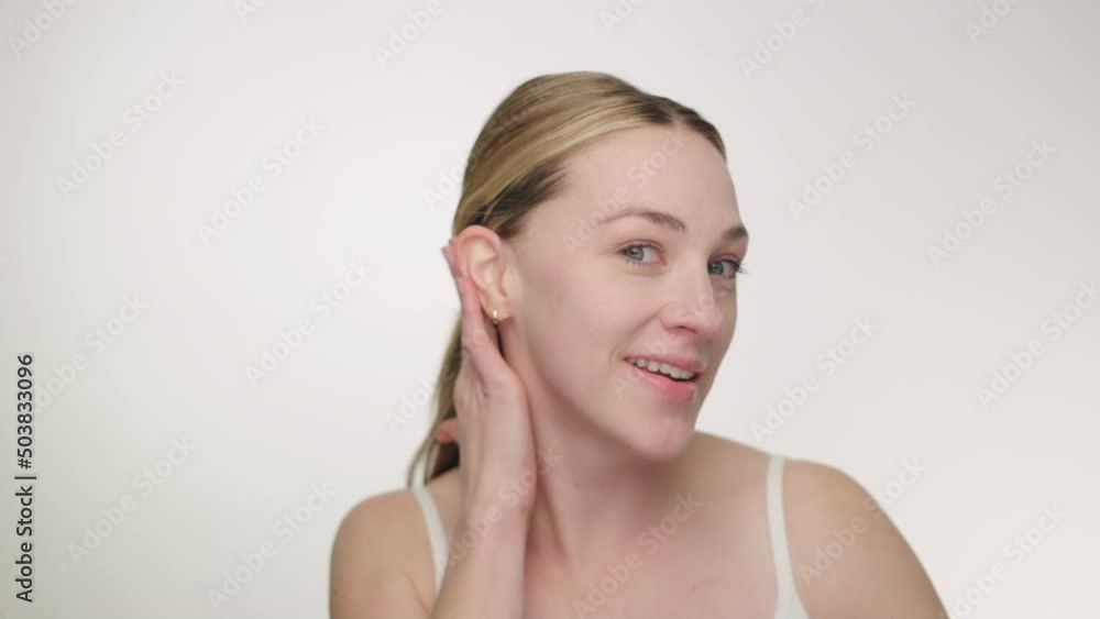 Pretty blonde model raises eyebrows with funny expression, straightens hair Pretty blonde model raises eyebrows with funny expression, straightens hair