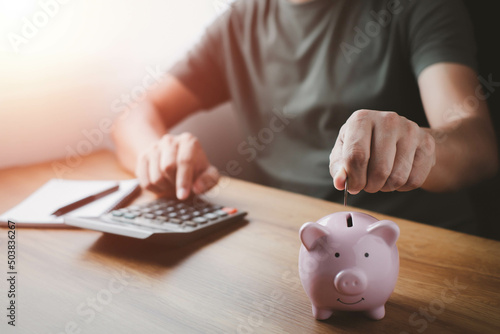 A man hand putting coins in pink piggy bank for account save money. Planning step up, saving money for future plan, retirement fund. Business investment-finance accounting concept. photo