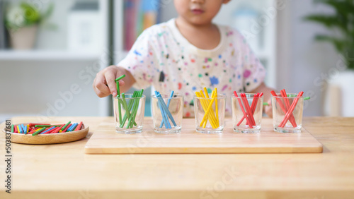 Unidentified hands of little boy learning to sorting the color rod to the glass, concept of homeschool, montessori, freedom, education, activity for child development and sensory activity for kid.