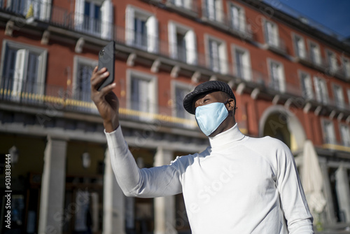 Closeup shot of a black man holding his phone wearing a turtleneck-concept of the new normal photo