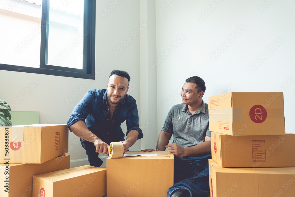 LGBTQ couples are packing boxes to move house. They lived happily ever after, covering the boxes with tape to prepare them for transport. LGBTQ couples are packing boxes to move house. They lived happily ever after, covering the boxes with tape to prepare them for transport.