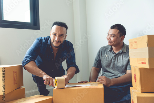 LGBTQ couples are packing boxes to move house. They lived happily ever after, covering the boxes with tape to prepare them for transport. photo