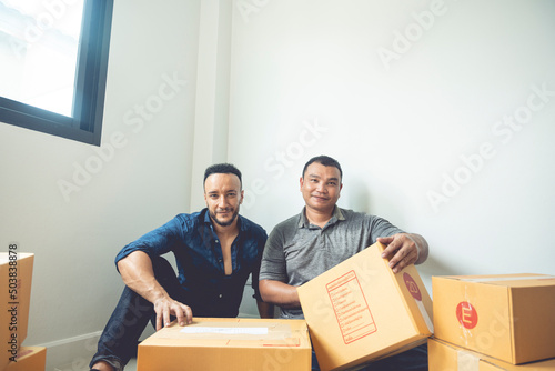 LGBTQ couples are packing boxes to move house. They lived happily ever after, covering the boxes with tape to prepare them for transport. photo