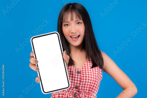 Beautiful Asian woman cute girl in red dress with bangs hair style smiling good mood showing big smart phone with blank screen , white screen isolated blue background , Mock up Image © suphaporn