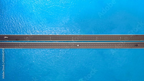 aerial view of The traffic on the bridge is fluent in traffic, contrasting with the blue water surface.