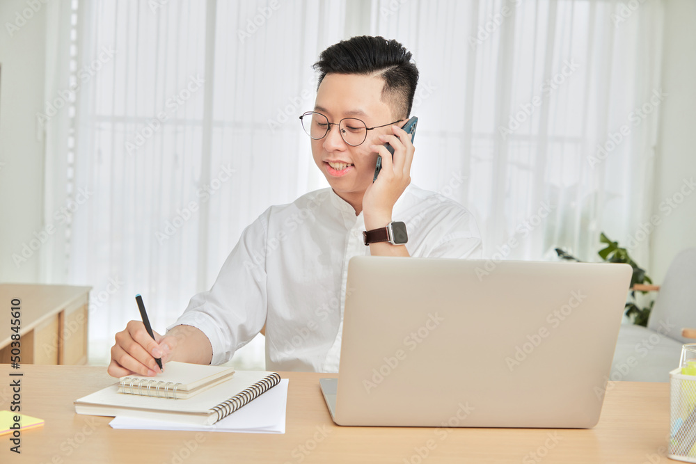 A moment of young man working with laptop and cellphone at home in living room background A moment of young man working with laptop and cellphone at home in living room background