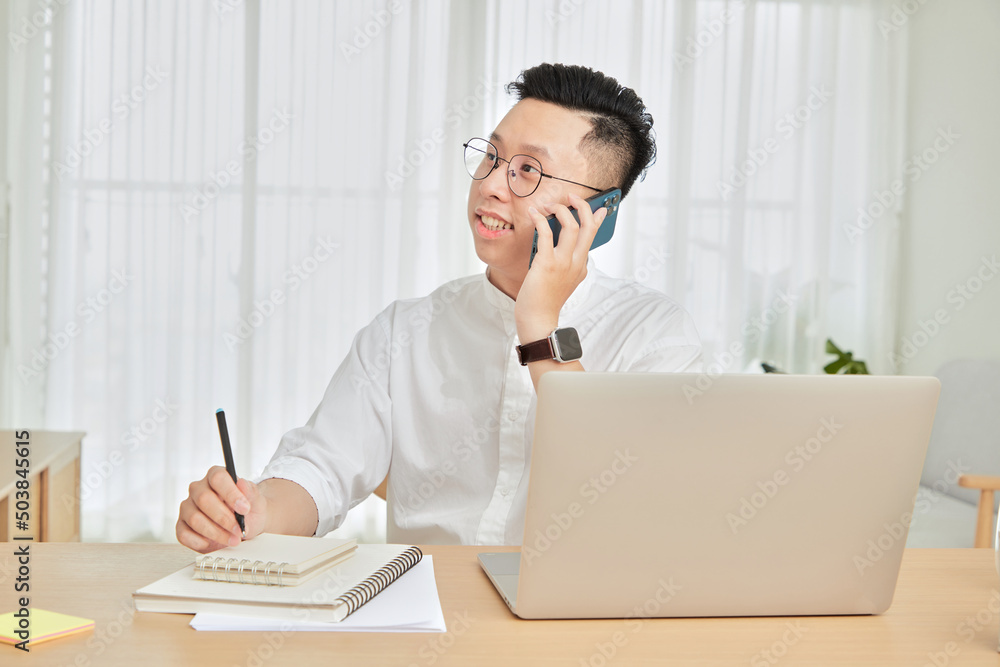 A moment of young man working with laptop and cellphone at home in living room background A moment of young man working with laptop and cellphone at home in living room background
