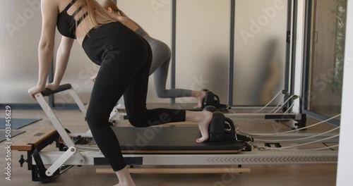Two fit pregnant woman work on Pilates machines