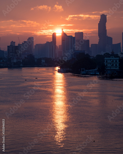 Sunrise  on Bangkok City   (sun between biuldings  over the river )  chao Phraya river. photo