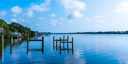 Blue water view with private wooden piers on the Sebastian River in Little Hollywood, Mikko, Florida. Panoramic photo in blue tones © Sergey + Marina