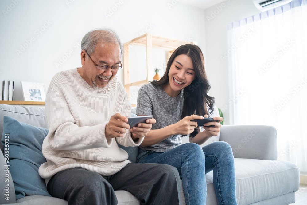 Asian senior father and daughter play game on phone together in house. Asian senior father and daughter play game on phone together in house.