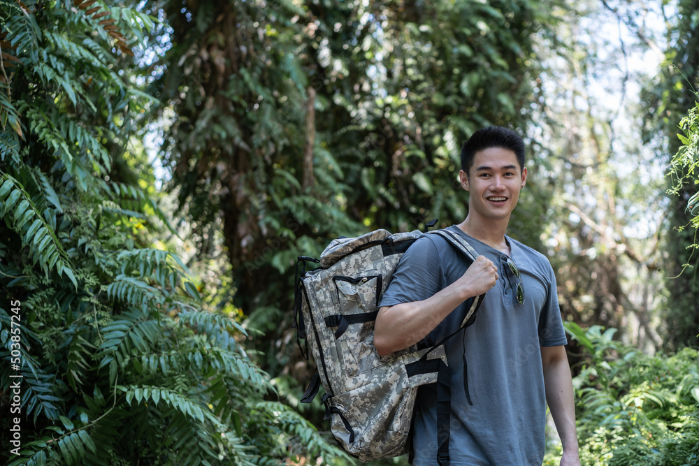 Fototapeta premium Portrait of Asian handsome man backpacker traveling alone in forest. 