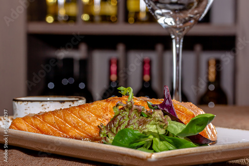 Delicious salmon fillet, rich in omega 3 oil, aromatic spices and lemon on fresh lettuce leaves on rustic wooden background. Healthy food, diet and cooking concept. With copy space.