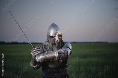 A knight in the armor and helmet with the sword battles on the battlefield concept.