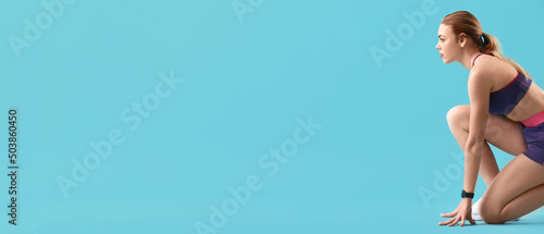 Sporty female runner in crouch start position on light blue background with space for text