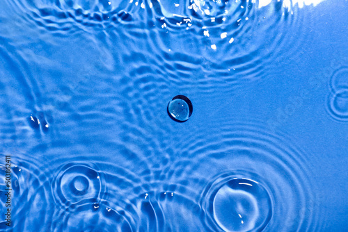 Clean water with splashes on color background