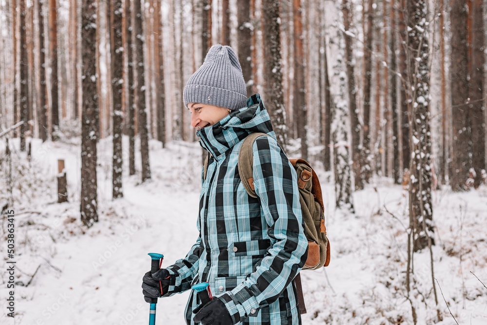 Fototapeta premium Nordic walking. Active sports. Young athletic woman practicing walking outdoors. Winter snowy forest