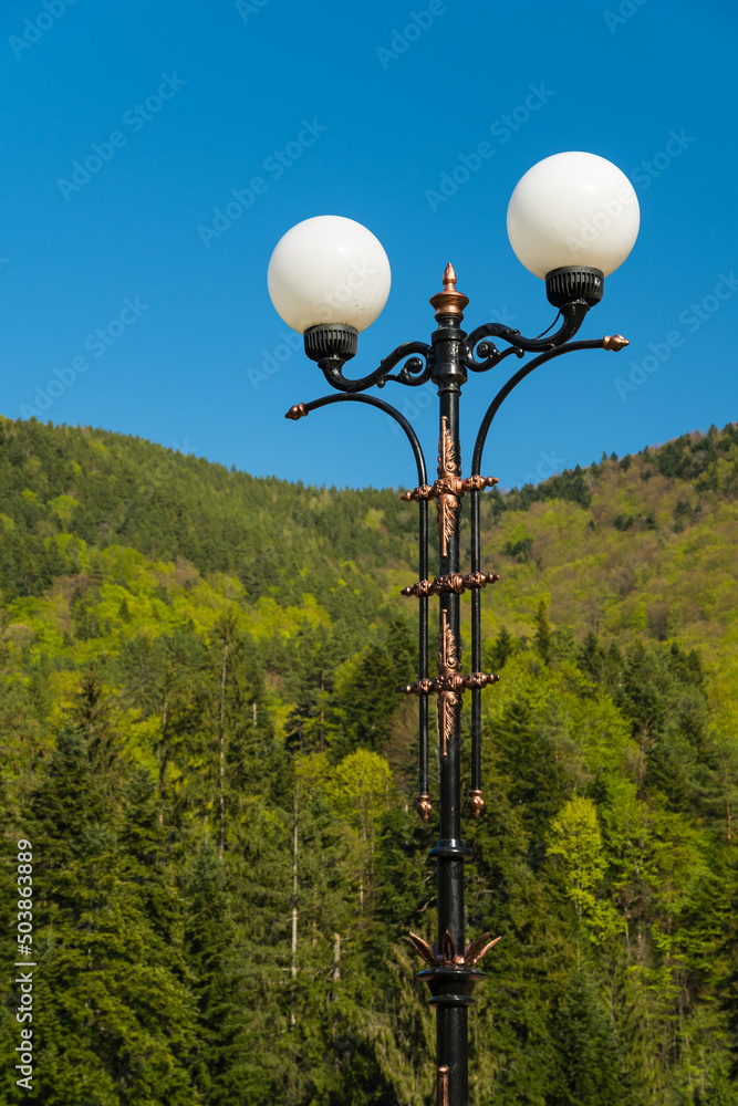 A Beautifully Crafted Street Lamp Facing the Blue Sky and Green Mountains A Beautifully Crafted Street Lamp Facing the Blue Sky and Green Mountains