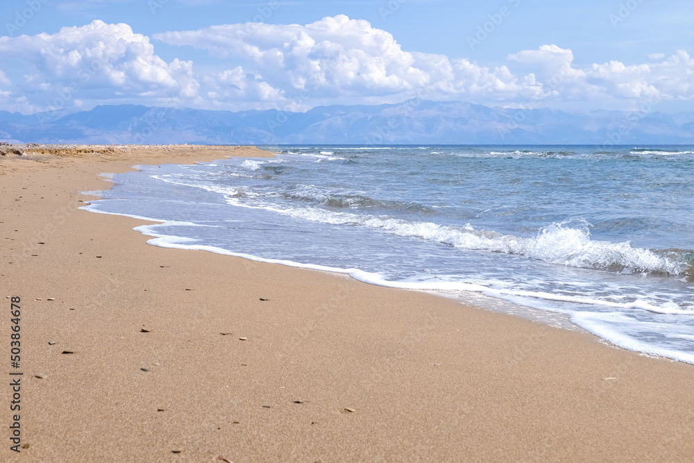 Sandy beach with sea waves at resort on sunny day Sandy beach with sea waves at resort on sunny day
