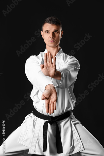 Man practicing karate on dark background photo