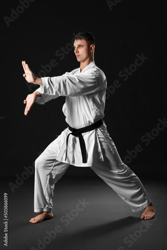 Man practicing karate on dark background