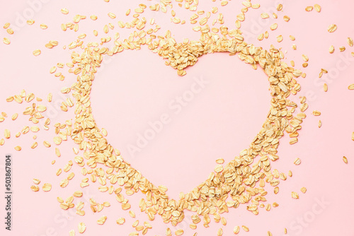 Heart made of raw oatmeal on pink background