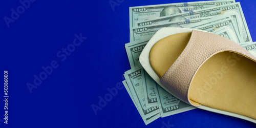 women's shoes on souvenir dollars and on a blue background. money out of focus. Banner for insertion into site. Horizontal image.