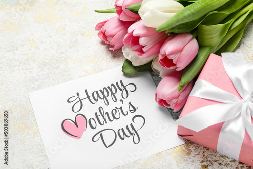 Card with text HAPPY MOTHER'S DAY, gift box and bouquet of tulips on grunge background